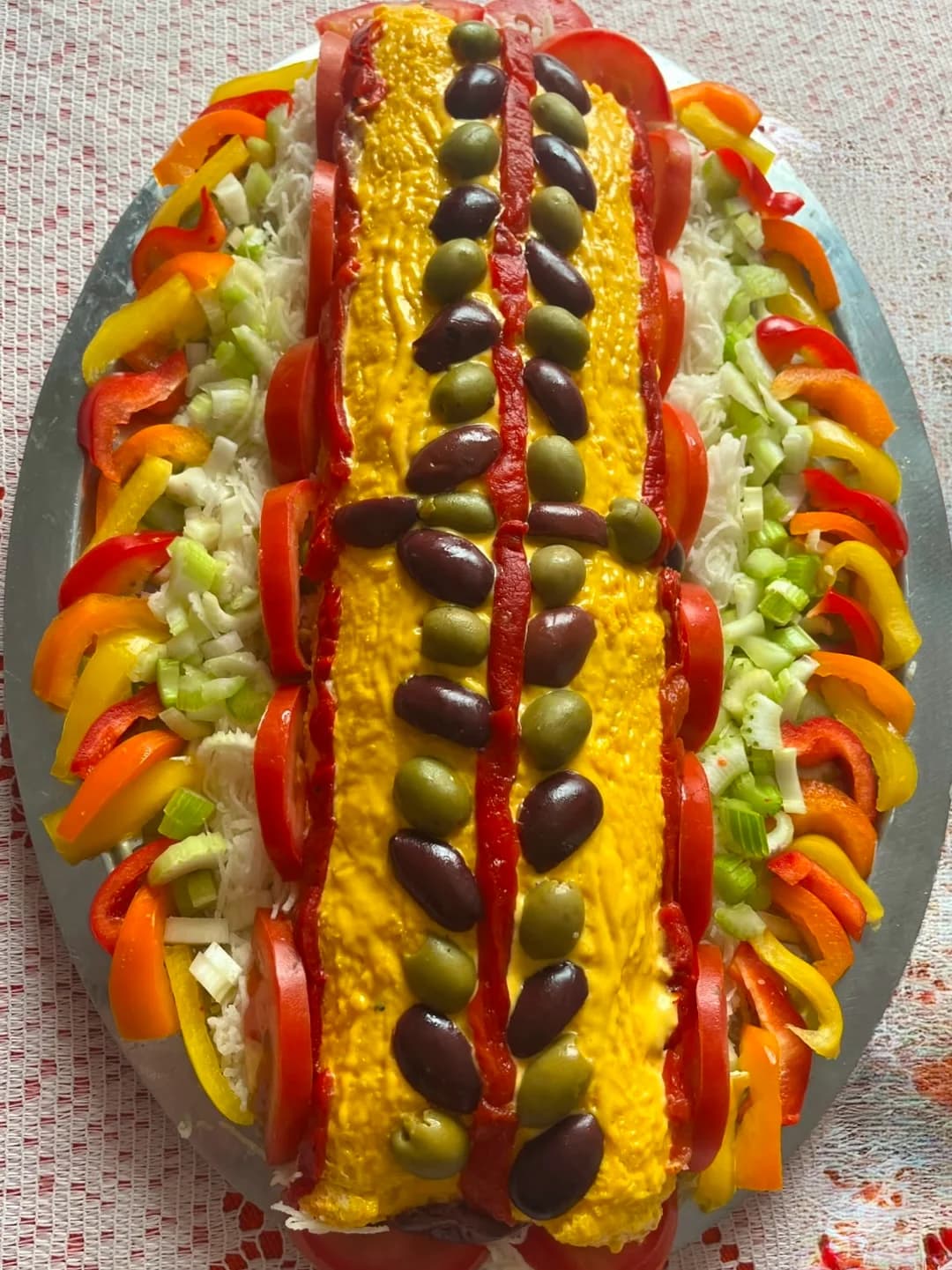 A colorful dish called Pionono with olives, bell pepper, tomato, and lettuce